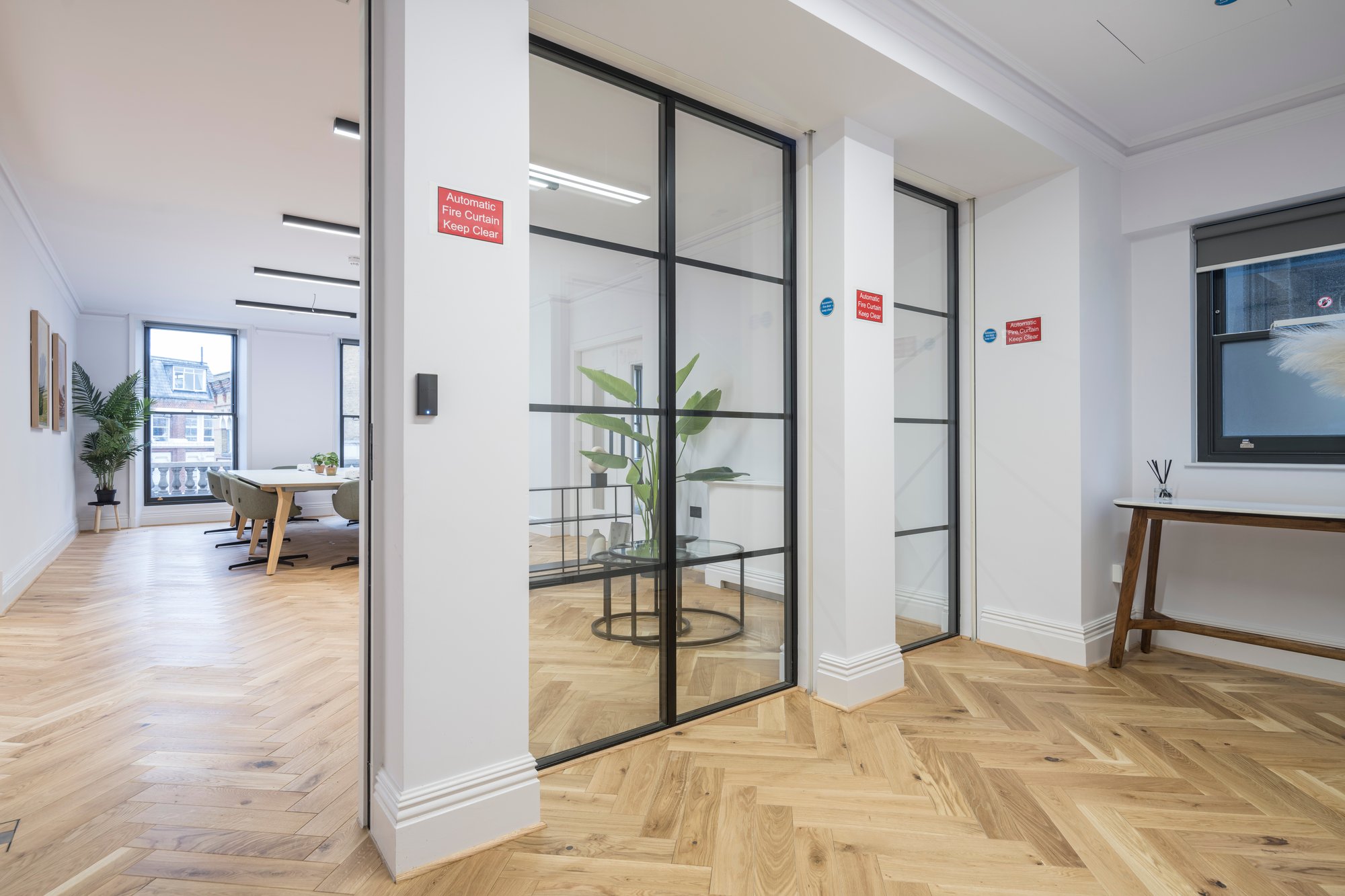 office area with glass partitioning and linear lighting